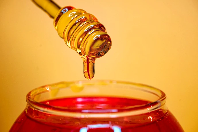 clear glass bottle pouring red liquid on clear drinking glass